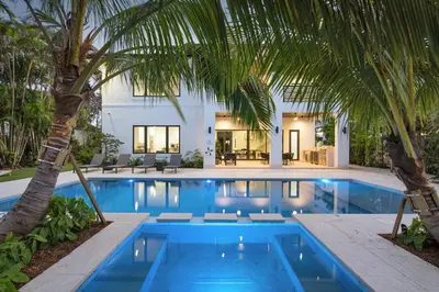 a pool with palm trees in front of a house at Villa in Coral Gables with Pool Jacuzzi Game Room in Miami