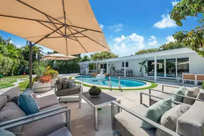 an outdoor patio with a pool and a large umbrella at Miami Paradise - Htd Pool, Mini Golf, Playground, BBQ, Arcade Machine, baby items in Miami