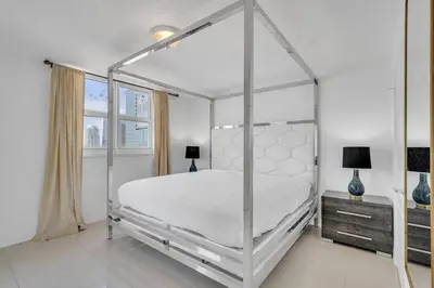 a white bedroom with a canopy bed and a window at Luxurious private unit with parking in Miami