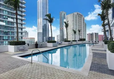 a large swimming pool with palm trees and buildings at Luxurious private unit with parking in Miami