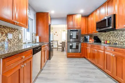 a large kitchen with wooden cabinets and stainless steel appliances at Casa Tropicana - Heated Pool, Game Room & Mins from beach in Hallandale Beach