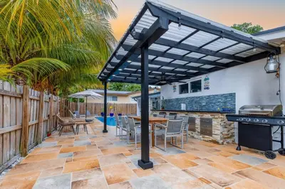 a patio with a table and chairs under a pergola at Casa Tropicana - Heated Pool, Game Room & Mins from beach in Hallandale Beach