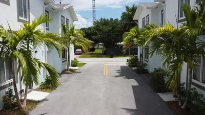 a street between two white houses with palm trees at Sistrunk Shades Villa #5 - New Townhome in Downtown Fort Lauderdale in Fort Lauderdale