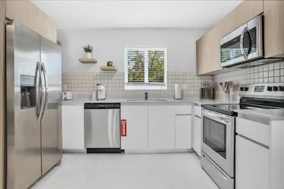a kitchen with white cabinets and stainless steel appliances at Sistrunk Shades Entire Compound 5 Homes 50 Guests in Fort Lauderdale