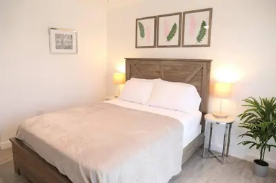 a bedroom with a bed with two lamps and a plant at Insta Worthy Modern Bungalow in Homestead