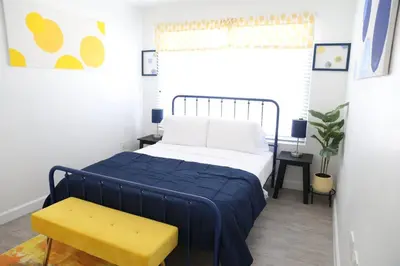 a bedroom with a blue bed and a yellow bench at Insta Worthy Modern Bungalow in Homestead