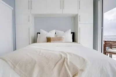 a white bedroom with a large white bed with a window at Chic Penthouse: 3BR x Pool x Gym x 2 Parking Spots in Miami
