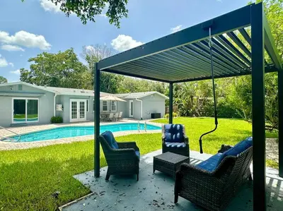 a covered patio with chairs and a table and a pool at Oasis in Plantation South Florida in Plantation