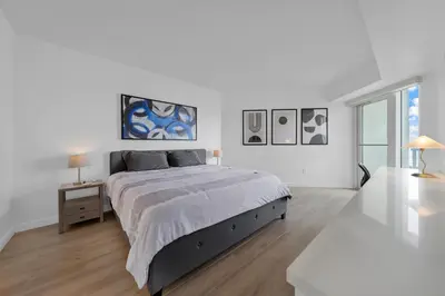 a white bedroom with a large bed and a table at 1-BD Condo in Coconut Grove - Water Views in Miami