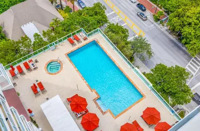 an overhead view of a swimming pool with red umbrellas at 1-BD Condo in Coconut Grove - Water Views in Miami