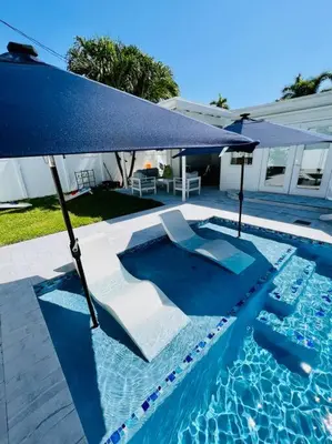 a swimming pool with a blue umbrella and chairs at Designer Pool & Family Dream Home in Hollywood