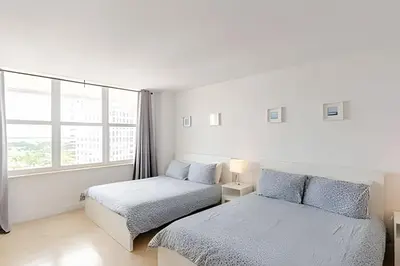 a white bedroom with two beds and a window at Pavilion -Amazing bay sunset-Miami Beach in Miami Beach
