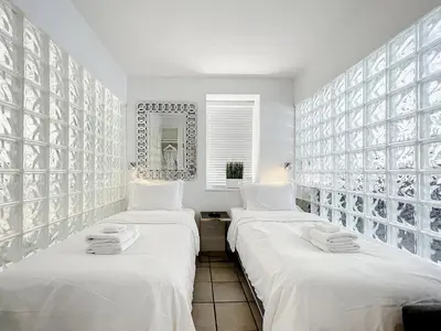 two beds in a room with white walls at CasaGrandeSouthBeach by AmericanVacationLiving 4RM in Miami Beach