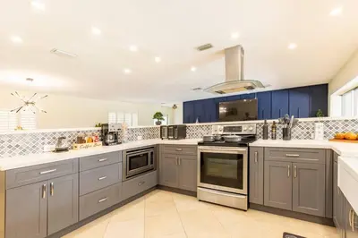 a large kitchen with blue cabinets and appliances at Spacious 4 Bedroom 3 Bathroom House with Heated Pool and Outdoor Shower close to FFL Airport and Cruise Port in Plantation
