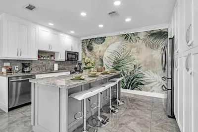 a kitchen with white cabinets and a tropical wallpaper at Miami Luxury Home! Next to Miami airport and beach in Miami