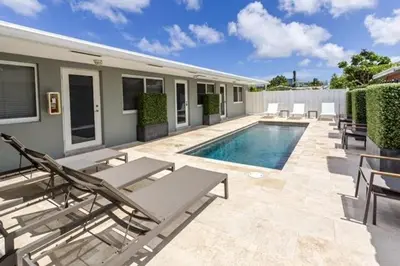 a swimming pool with chaises and chairs next to a house at Wiltonplex C in Fort Lauderdale