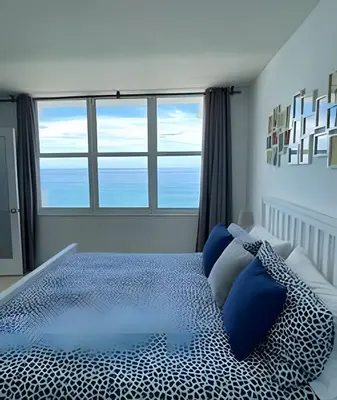 a bedroom with a bed with blue pillows and windows at Pavilion - Great ocean view -Miami Beach in Miami Beach