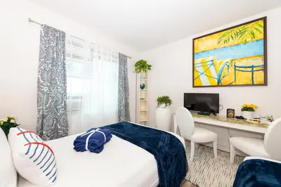 a bedroom with a bed and a desk with a television at 6768 Collins Miami Stays in Miami Beach
