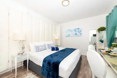 a white bedroom with a bed and a desk at 6768 Collins Miami Stays in Miami Beach