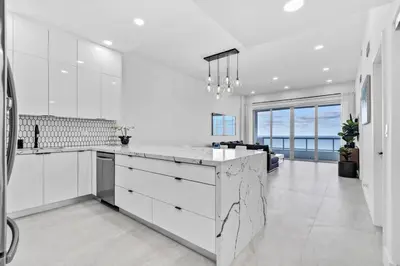 a kitchen with white cabinets and a large island at OceanFront Luxury Penthouse 2 Bedrooms with Direct Ocean View in Miami Beach
