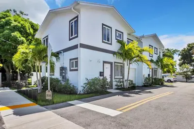 a white building with palm trees in front of it at Sistrunk Shades Villas Units #1 & #2 Combined in Fort Lauderdale