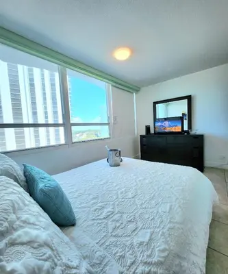 a bedroom with a large white bed with a television at Beachfront Property Pool Gym Tennis Miami Beach! in Miami Beach
