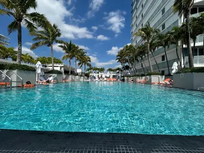 a large swimming pool with palm trees and a building at Beachfront-Spacious W Residence in Fort Lauderdale