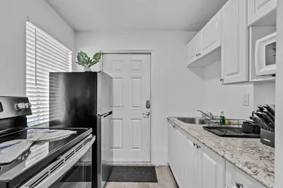 a kitchen with white cabinets and a black refrigerator at Lovely 2 bedroom Studios-Suite Walking Distance To Ocean in Hollywood