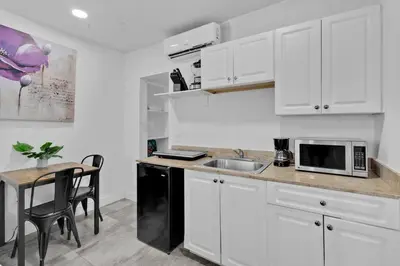 a kitchen with white cabinets and a sink and a table at Lovely Studio Walking Distance To Ocean - Suite 8 in Hollywood