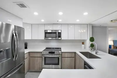 a kitchen with stainless steel appliances and wooden cabinets at Calypso - Gorgeous Miami Renovated Spacious Condo! in Miami