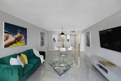 a living room with a green couch and a tv at Shock Wave! NEW Renovated Condo With Water Views! in Miami