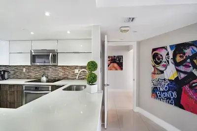 a kitchen with white cabinets and a poster of two faces at Dreamscape! Renovated and spacious 1 bedroom condo in Miami