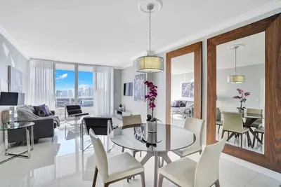 a dining room and living room with a table and chairs at Sky High Penthouse! Water & City Views (top floor) in Miami