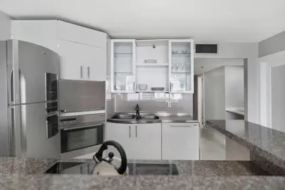 a kitchen with white cabinets and a stainless steel refrigerator at Dance with me! Water and Park Views! in Miami