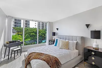 a bedroom with a bed and a desk and a window at The Palms! Direct water view corner condo in Miami