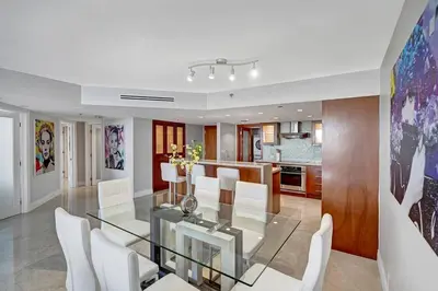 a dining room and kitchen with a glass table and white chairs at Only in My Dreams! Direct Water View Luxury Condo in Miami
