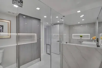 a bathroom with a glass shower and a sink at A Wave From It All! Direct water views! in Miami
