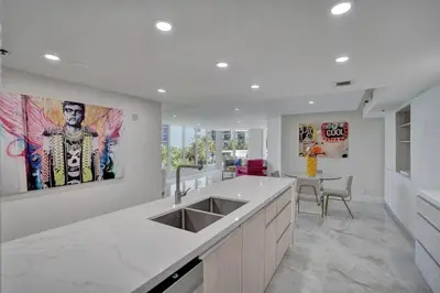 a white kitchen with a sink and a table at GoldDust - Water and City Views! in Miami