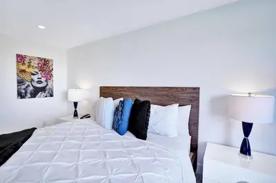 a bedroom with a large white bed with two lamps at Feels Like Summer ~ Panoramic Water Views! in Miami