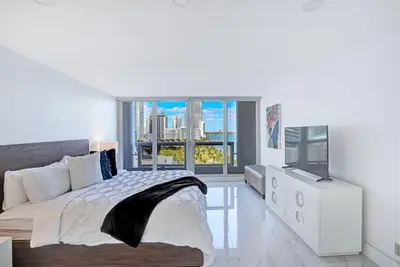 a white bedroom with a bed and a television at Feels Like Summer ~ Panoramic Water Views! in Miami