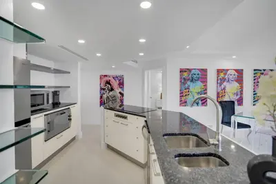 a kitchen with two sinks and paintings on the wall at Walking on Water! Water Views! in Miami