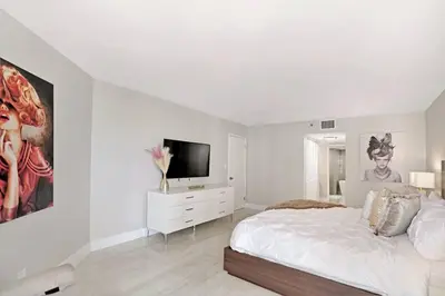 a white bedroom with a bed and a flat screen tv at Sun-Kissed & Sunshine! Direct Water and City Views in Miami