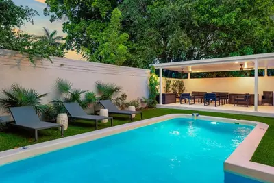 a swimming pool in a backyard with chairs and a table at Beautiful Villa with heated pool Must seen! in Miami