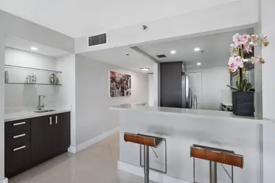 a kitchen with a sink and a counter with two stools at Meet Me in Miami! Impressive Miami Skyline Views in Miami