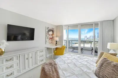 a white bedroom with a television and a balcony at Meet Me in Miami! Impressive Miami Skyline Views in Miami