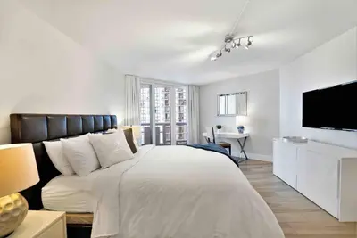 a white bedroom with a large bed and a tv at Aqua Marina! Water & City Views! in Miami