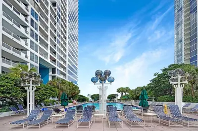 a patio with chairs and a pool in front of a building at Over The Moon! Miami Skyline and Water Views! in Miami