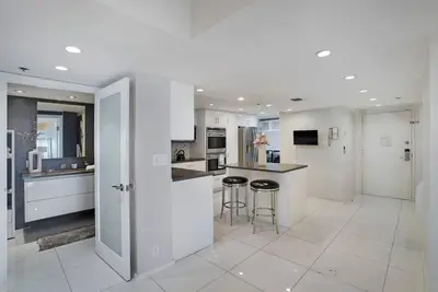 a white kitchen with a counter and stools in it at Seas The Day! Complete Panoramic Water Views in Miami