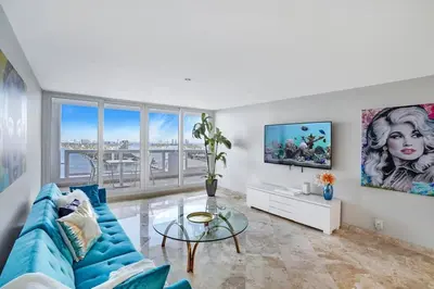 a living room with a blue couch and a glass table at First Class! - Crystal clear water views! in Miami