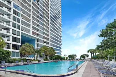a swimming pool in front of a tall building at Good Morning Beautiful! Direct Water Views in Miami
